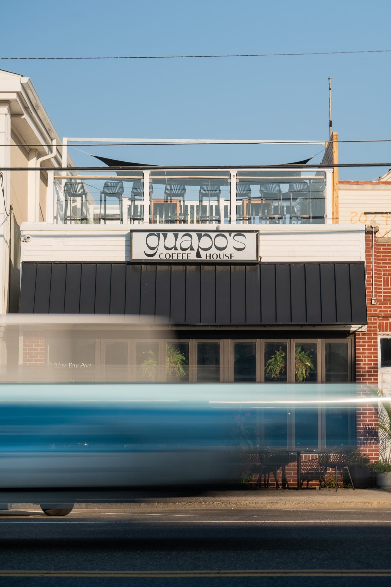 Truck streaking past a coffee house storefront with rooftop patio in long-exposure morning light