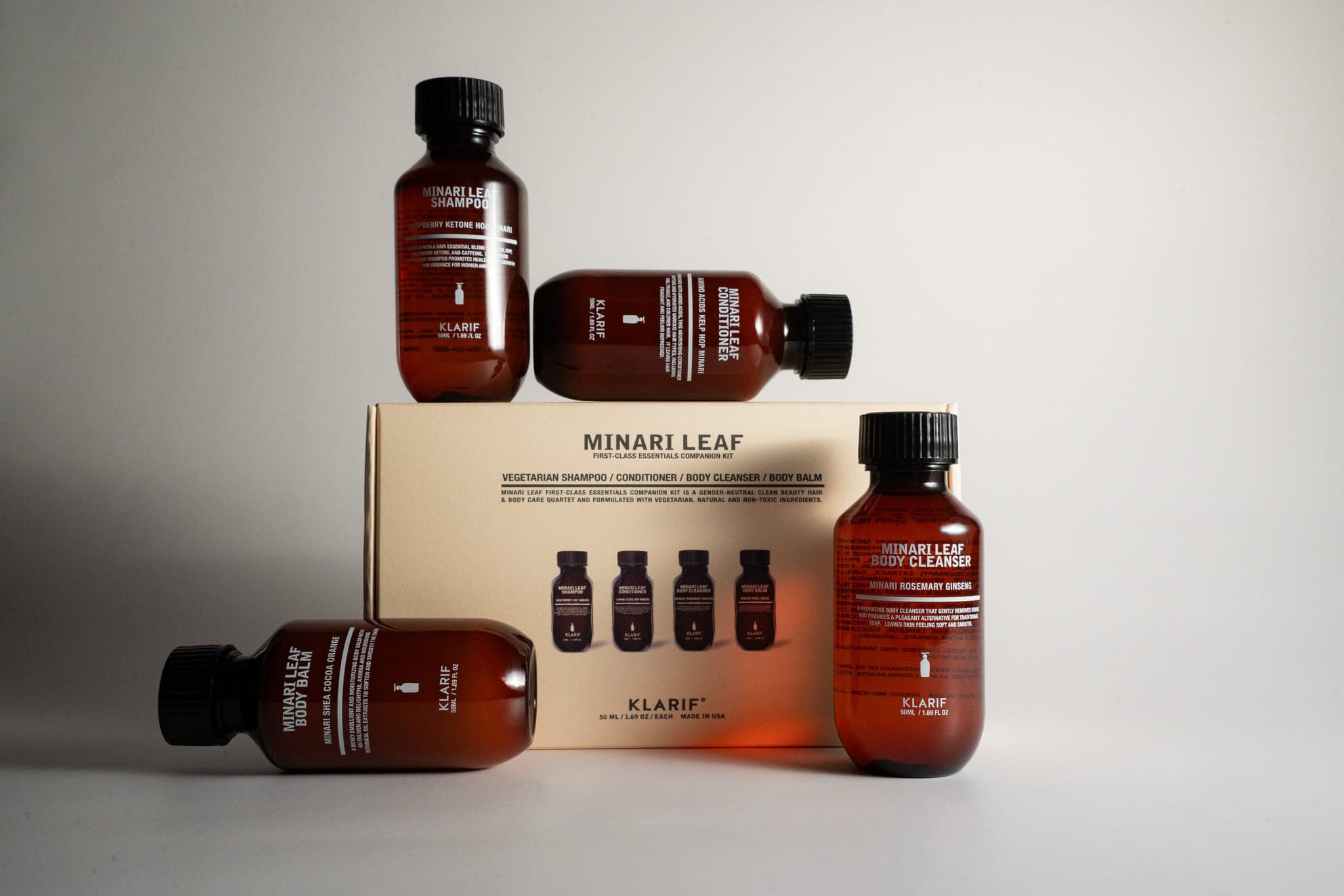Minari Leaf travel-size hair and body care set arranged around its cream box on a neutral backdrop